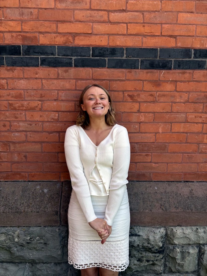 Portrait of artist Bre-Anna Murphy standing before a brick wall.